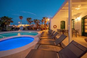 a swimming pool with chaise lounge chairs next to a house at Villa Milan in Puerto del Carmen