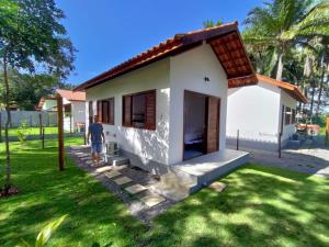 a man standing in front of a small house at Chalés do Maestro in Ilha de Boipeba