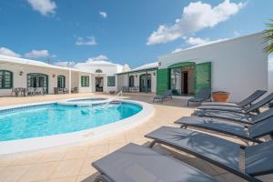 a villa with a swimming pool and lounge chairs at Villa Milan in Puerto del Carmen