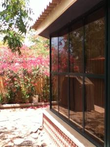 a window of a house with flowers in the background at Spacious, Sunny, Cozy & Secure in Mindelo
