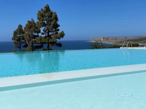 una piscina azul con un árbol en el fondo en CALA AZZURRA MACARI Bed and Breakfast and Holidays House, en Macari