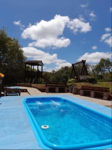 a large blue swimming pool with a playground in the background at Sítio pousada e Refúgio lazer e eventos in Santana do Livramento