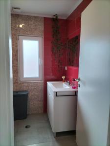 La salle de bains est pourvue de murs rouges, d'un lavabo et d'une fenêtre. dans l'établissement Casa Davó Cinda, à Paredes de Coura