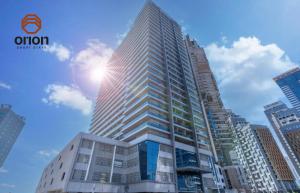 a tall building with the sun in the sky at Cosy Studio with Canal Views by Orion Short Stays - 521 Monthly Offer in Dubai