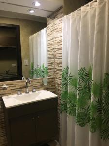 baño con lavabo y cortina de ducha con plantas en Departamentos Casa del Parque en Necochea