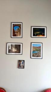 four pictures are hanging on a white wall at Porto Levante in Ermoupoli