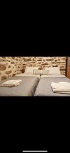 two beds with white pillows and a stone wall at Porto Levante in Ermoupoli