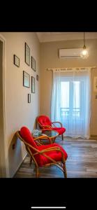 duas cadeiras com almofadas vermelhas num quarto com uma janela em Porto Levante em Ermoupoli
