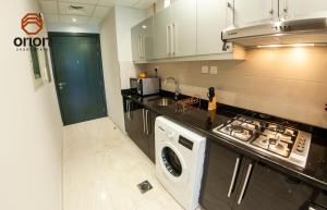 a kitchen with a stove and a washing machine at Cosy Studio with Canal Views by Orion Short Stays - 521 Monthly Offer in Dubai