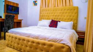 duże łóżko z dużym żółtym zagłówkiem w pokoju w obiekcie KUNN Apartments w Asabie