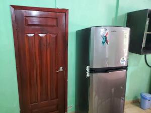 a refrigerator next to a wooden door in a room at Apartamentos y Hostal RUDON #4 in Puerto Cortés