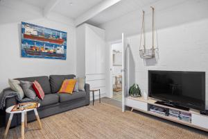 un soggiorno con divano grigio e TV a schermo piatto di Sorrento Beach House a Sorrento