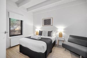 a white bedroom with a bed and a couch at Sorrento Beach House in Sorrento