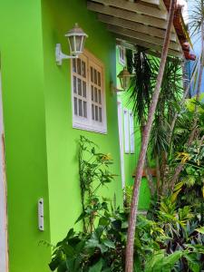 uma casa verde com uma janela branca e plantas em SUÍTES Caminho do Mar em Abraão