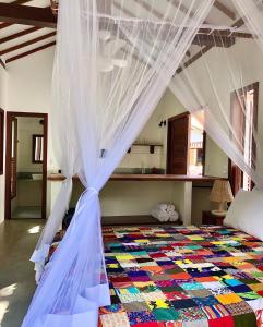 a bedroom with a bed with a mosquito net at Chalés do Maestro in Ilha de Boipeba +41 photos