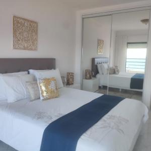 a white bedroom with a large bed and a mirror at Ocean Blue II in Quarteira
