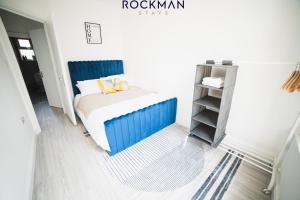 een kleine slaapkamer met een blauw bed en een plank bij 12B Alexandra Street - Stylish Apartment in the Heart of Southend on Sea by Rockman Stays in Southend-on-Sea