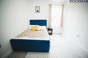 ein blaues Bett in einem Zimmer mit Fenster in der Unterkunft 12B Alexandra Street - Stylish Apartment in the Heart of Southend on Sea by Rockman Stays in Southend-on-Sea