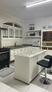 una cocina con armarios blancos y una barra con sillas en Casa de Férias em Atibaia Piscina Climatizada en Atibaia