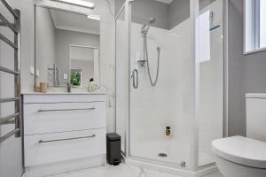 a white bathroom with a shower and a toilet at Our Happy Place - Waihi Beach Holiday Home in Waihi Beach +15 photos
