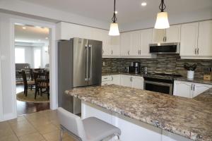 a kitchen with white cabinets and a stainless steel refrigerator at Lavish 4BR House Near Simcoe Lake & FH Resort in Innisfil