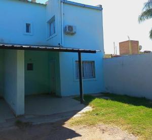 a white building with a porch next to a yard at Duplex 80 mts cubiertos con garaje in San Fernando del Valle de Catamarca