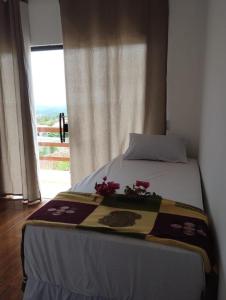 a bed with a blanket on it with a window at Chalé Aconchego da Serra in Serra de São Bento