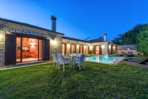 a backyard with a table and chairs and a pool at Astarte Villas - Kyveli Luxurious Private Villa in Zakynthos Town