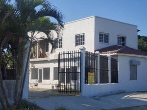 ein weißes Haus mit einem Tor und einer Palme in der Unterkunft Apartamentos y Hostal Rudon # 5 in Puerto Cortes