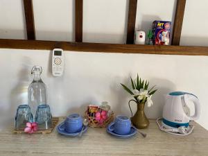 a shelf with dishes and cups and a bottle on it at Mustika Ocean Lodge in Gili Air
