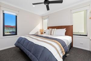 a white bedroom with a bed and two windows at BIG4 Bendigo Park Lane Holiday Park in Bendigo