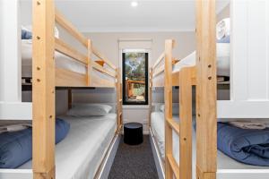 a dorm room with three bunk beds and a mirror at BIG4 Bendigo Park Lane Holiday Park in Bendigo