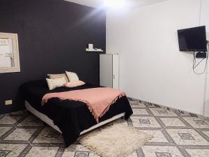 1 dormitorio con cama y pared negra en Arizona en Chascomús