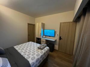 1 dormitorio con 1 cama y escritorio con TV en Habitación Cerezo en Palmerola, Comayagua, en Comayagua