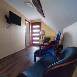 ein Wohnzimmer mit einem Stuhl und einem TV in der Unterkunft Acogedor departamento interior con acceso independiente y estacionamiento in La Serena