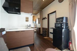 uma pequena cozinha com frigorífico e micro-ondas em Mt Fuji Glamping VILLA Kawaguchiko em Fujikawaguchiko