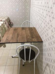 una mesa de madera con una silla blanca debajo en Kitinete en Chapecó