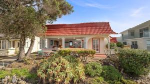 a house with a red roof and a yard at Beachside Bliss - Waiwera Beachfront Holiday Home in Orewa