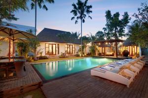 een zwembad met ligstoelen en een huis bij Kandahill Bali in Uluwatu