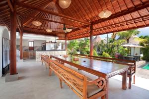 uma sala de jantar com uma grande mesa de madeira e bancos em Kandahill Bali em Uluwatu