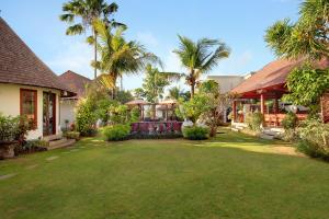 a yard with palm trees and a house at Kandahill Bali in Uluwatu