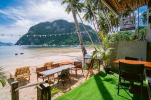 un restaurante en la playa con mesas y sillas en Banig Beach Resort El Nido, en El Nido