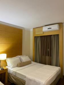 a bedroom with a bed and a window with a air conditioner at Flat Aeroporto Congonhas in São Paulo
