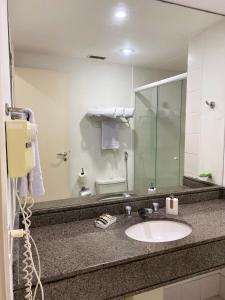 a bathroom with a sink and a large mirror at Flat Aeroporto Congonhas in São Paulo