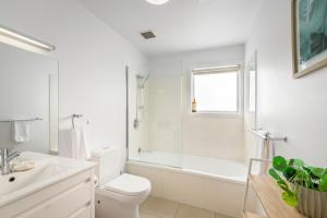 a white bathroom with a tub and a toilet and a sink at Bellerive Quay - 2 Bedroom Apartment - Free Parking - Free WIFI in Bellerive +17 photos