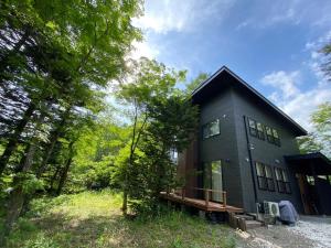 une maison noire au milieu de la forêt dans l'établissement 木漏れ日ハウス, à Karuizawa