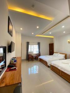 a hotel room with two beds and a television at Queen Hotel in Tuy Hoa