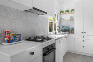 a kitchen with white cabinets and a stove top oven at Dicky Beach Original - 2 Bed Downstairs Studio 200m to Beach in Caloundra