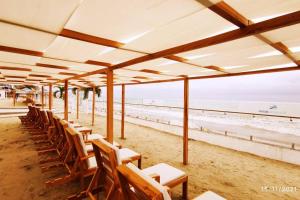 - une rangée de tables et de chaises sur la plage dans l'établissement Departamento Playero Fountaine Bleau Frente al Mar Tonsupa, à Tonsupa