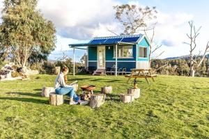 Chum CreekYarra Valley Tiny House - Tiny Stays的坐在小房子前面的木头上的女人